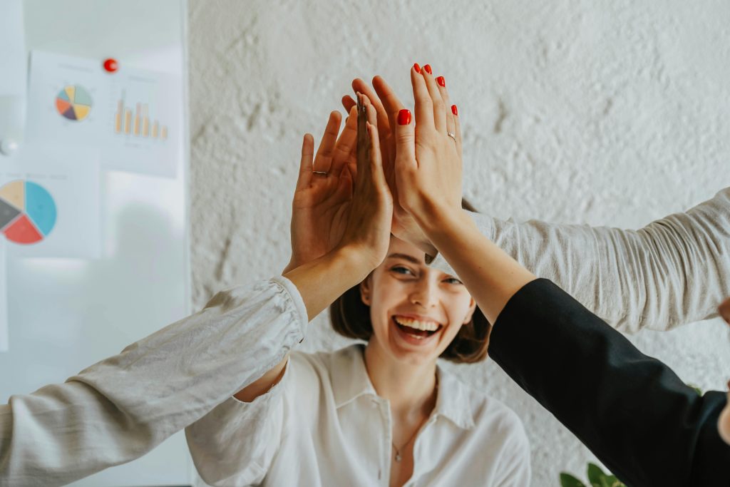 Happy colleagues high-fiving in a meeting, showcasing teamwork and success.